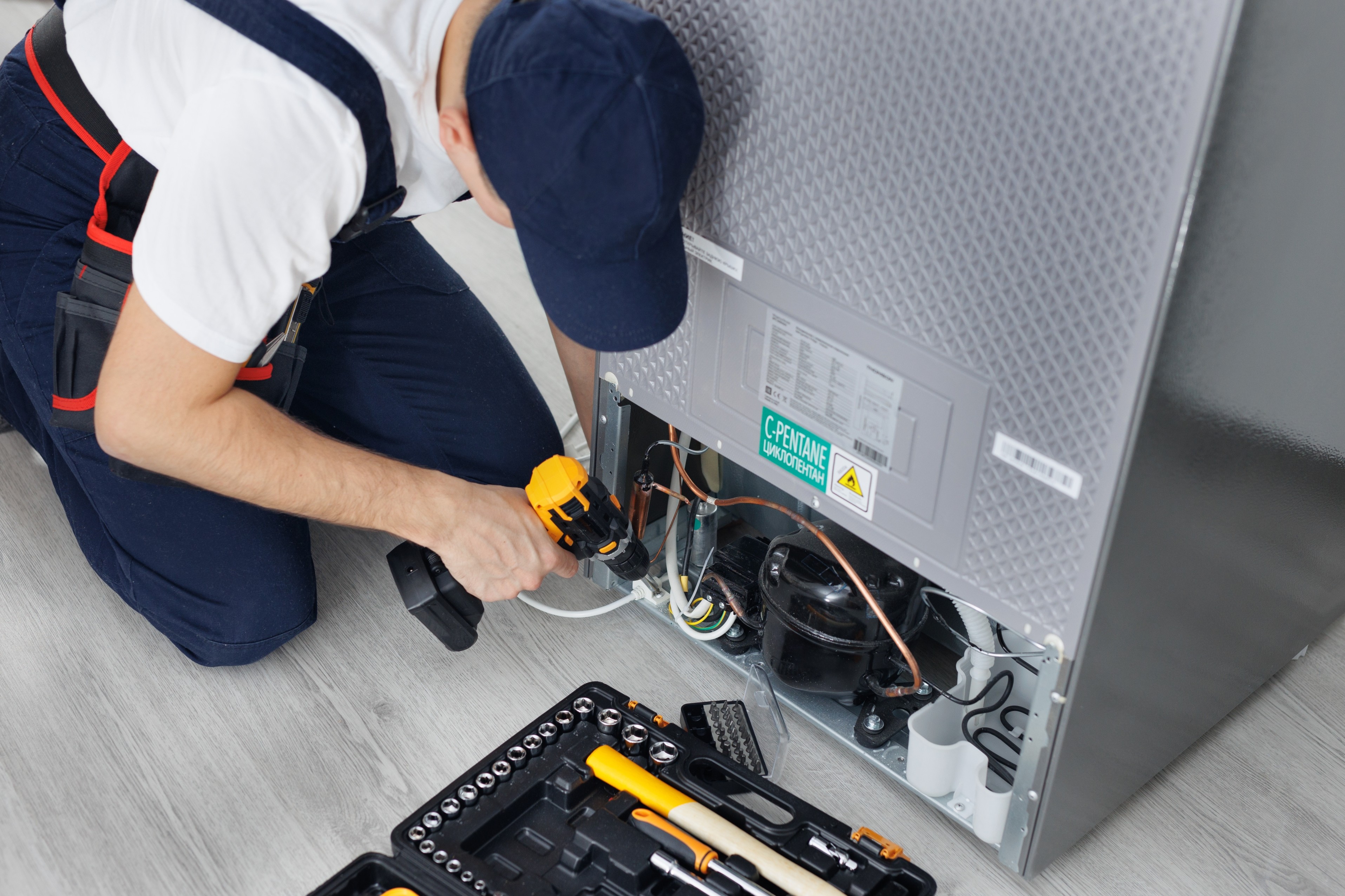 Technician repairing the back of a fridge