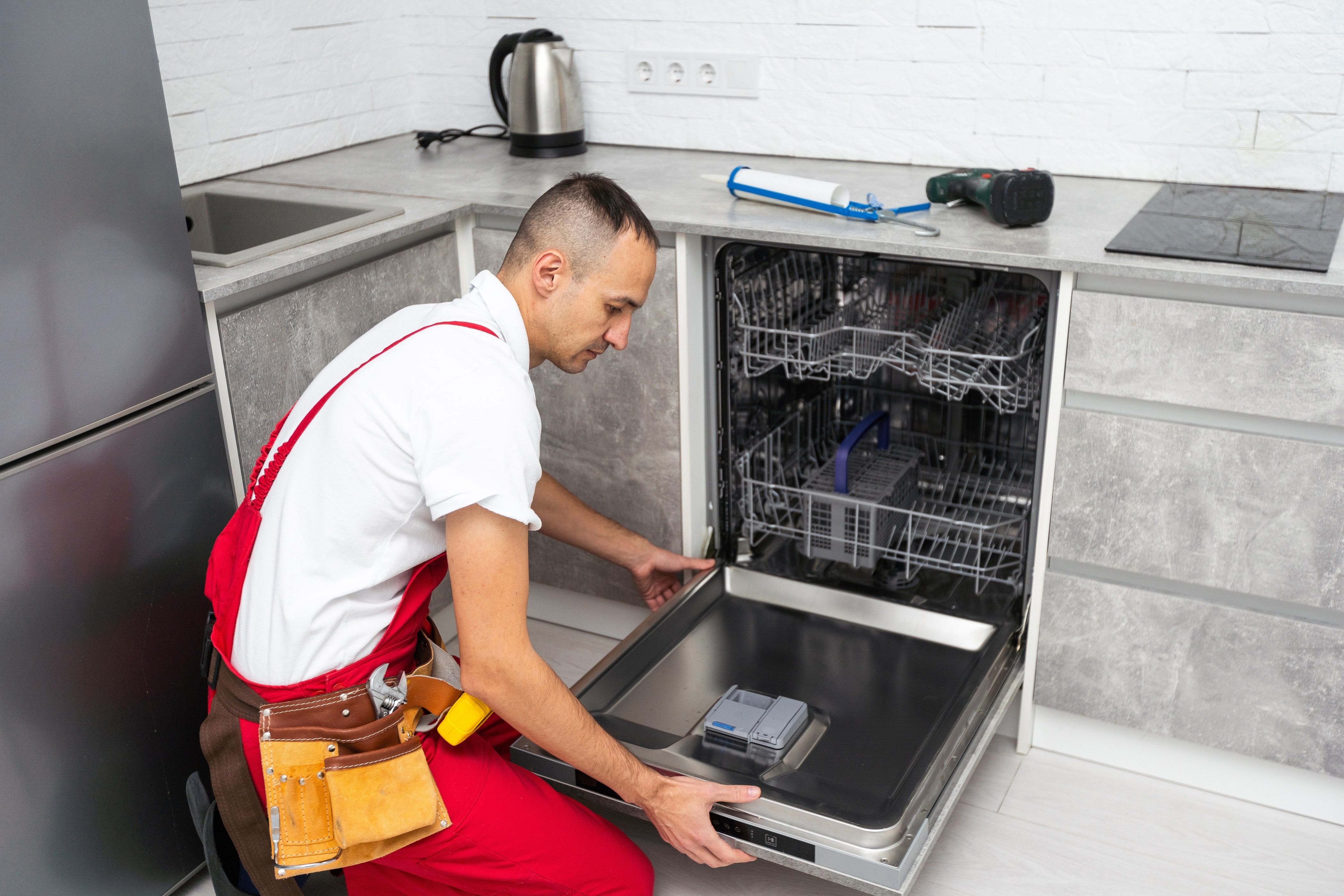Technician servicing an open dishwasher